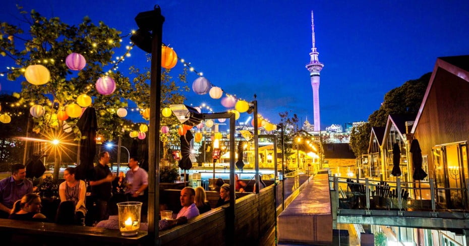 The Auckland Sky Tower and a busy bar at night. 