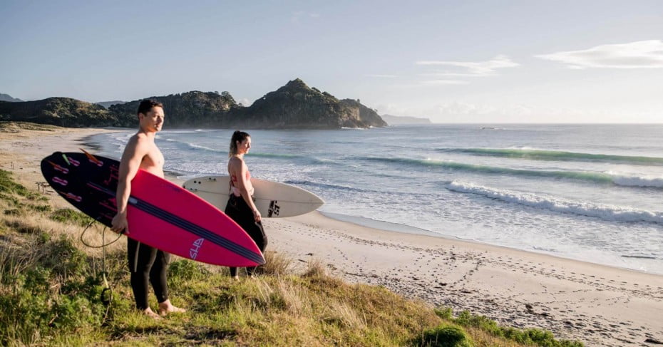 Surfers on the beach at Great Barrier Island. 