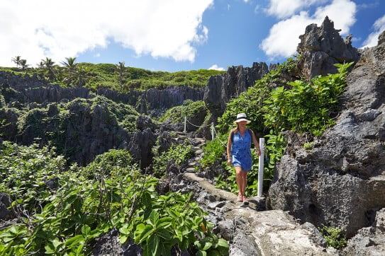 Lady in blue walking through rocky terrain, Niue, Pacific Islands. 